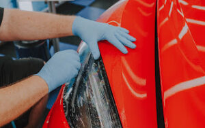 PPF being added and cut at the headlights of a red car