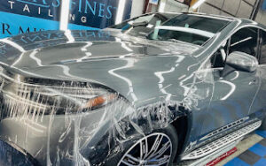 The front end of a silver car getting wrapped in paint protect film, aka PPF