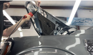 tucking the corners and details of a paint protection film over the hood of a vehicle