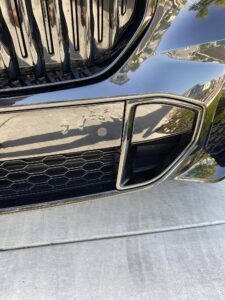 PPF peeling from the front bumper beside a grill 