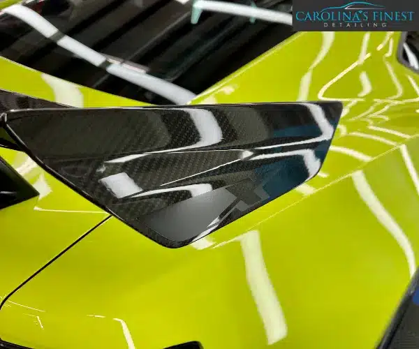 A side profile view of the luxury sedan in a professional workshop, highlighting the flawless, mirror-like reflections on the polished door panels.