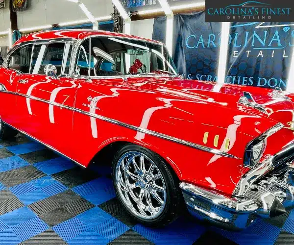 view of the polished vintage red car highlighting the iconic tail fins, chrome trim, and flawless glossy finish after a detailing service, referencing paint correction