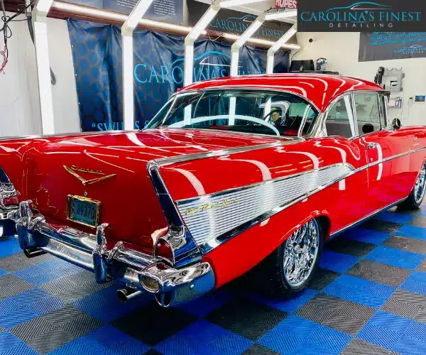 view of the polished vintage red car highlighting the iconic tail fins, chrome trim, and flawless glossy finish after a detailing service, referencing paint correction