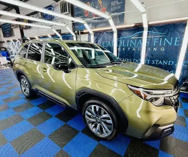 green Subaru SUV parked inside a brightly lit detailing bay, showing auto detailing in Charlotte NC