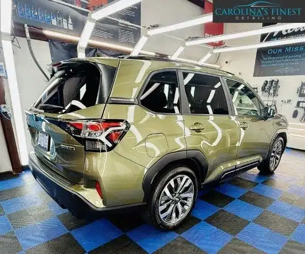green Subaru SUV parked inside a brightly lit detailing bay, showing auto detailing in Charlotte
